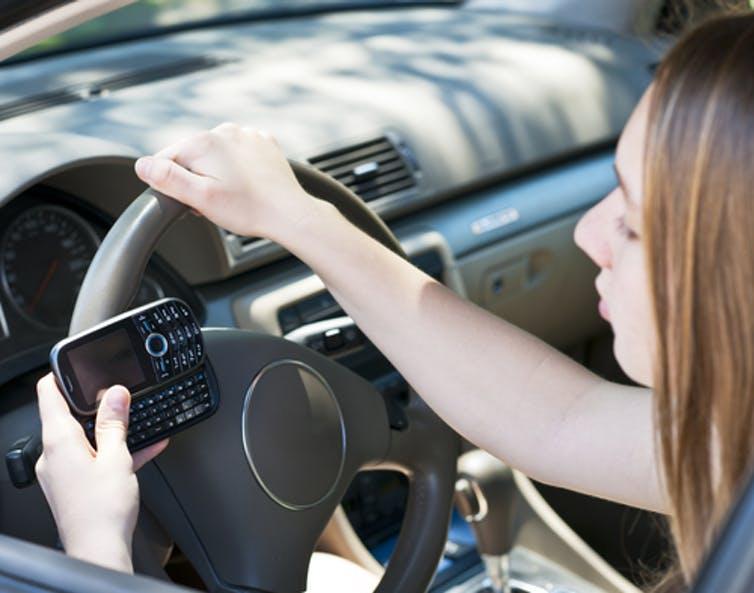 A teenager texts on her cellphone as she drives.