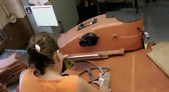 An employee at Wilson’s Ada, Ohio factory cuts football leather